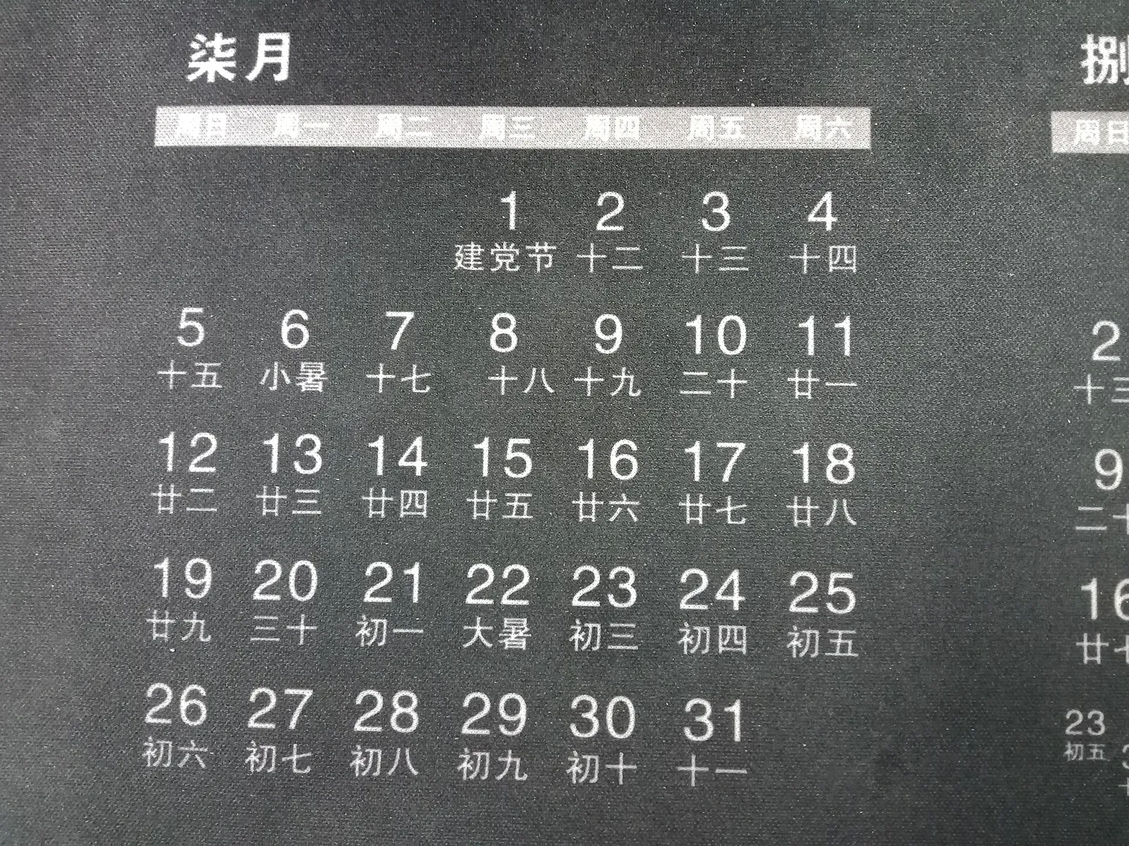 A close-up of a wall calendar page for July, with dates and Chinese lunar days.