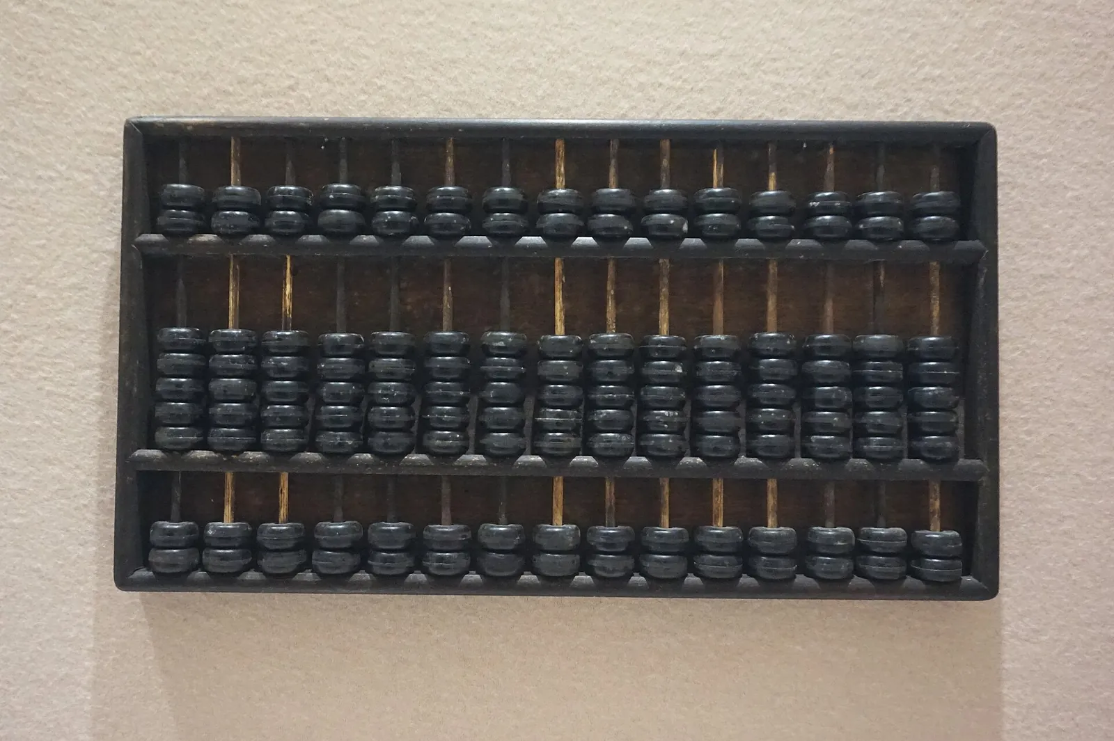 A traditional Chinese abacus mounted on a plain wall.