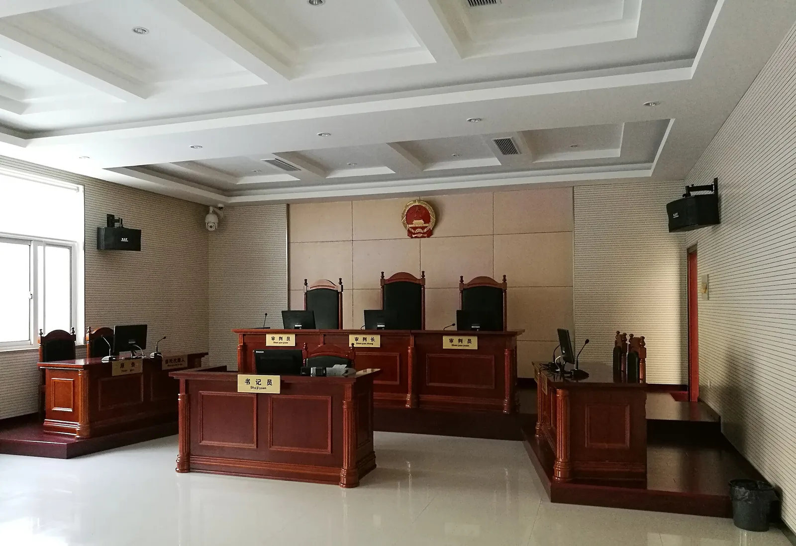 An empty courtroom in mainland China, with the judges' bench beneath the national emblem.