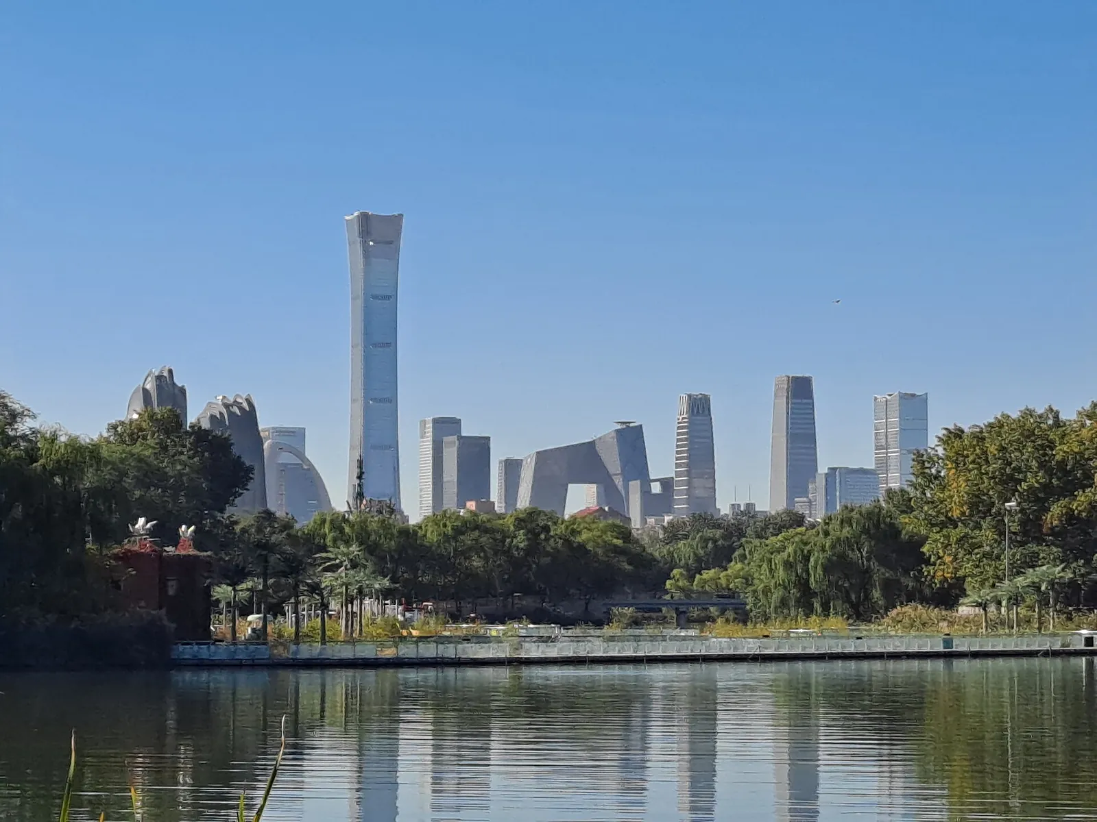A lake in Chaoyang Park, Beijing, with trees along the shore and the city skyline beyond.