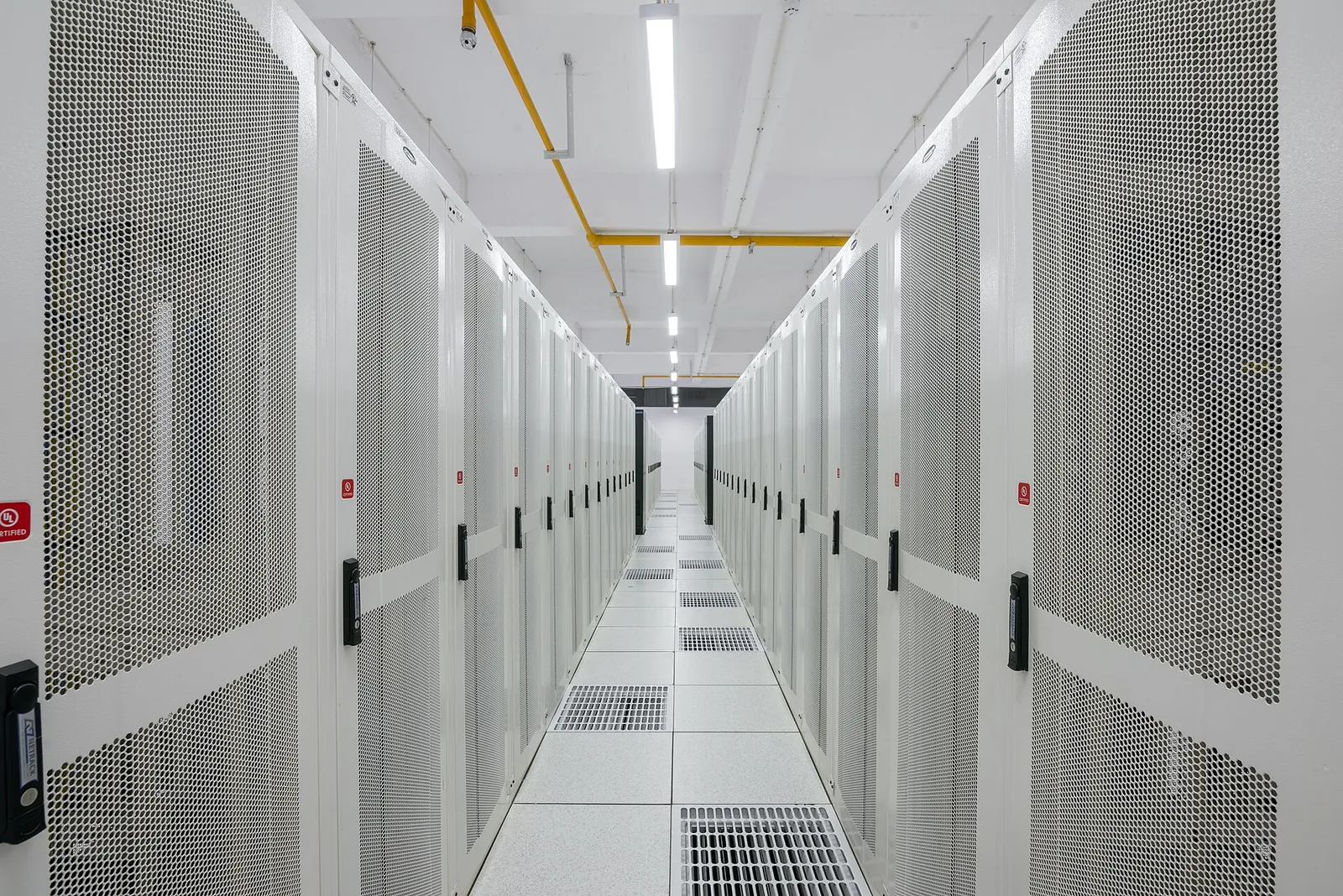 A long aisle between rows of white server cabinets in a data centre.