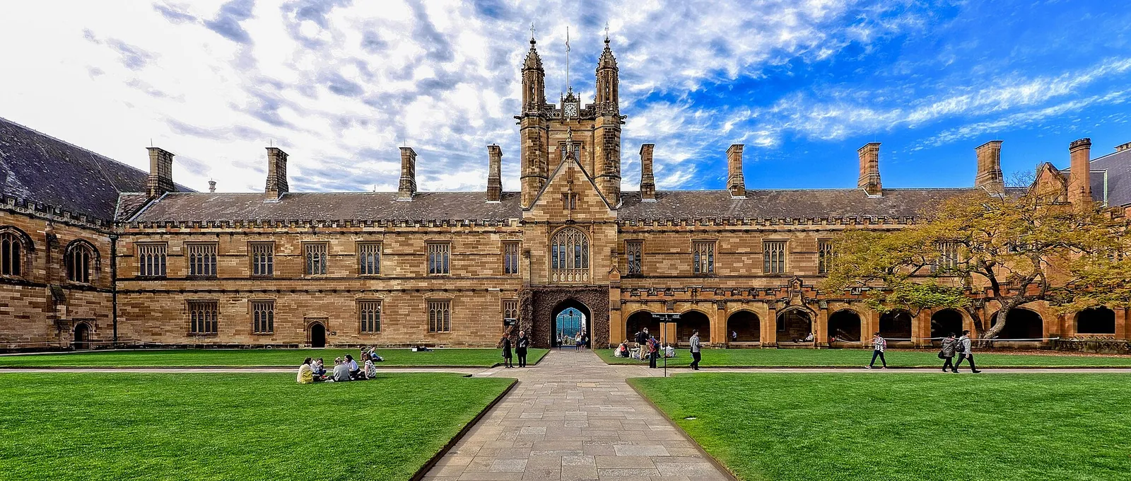 The sandstone Main Quadrangle of the University of Sydney, with lawns and a path leading to the clock tower.