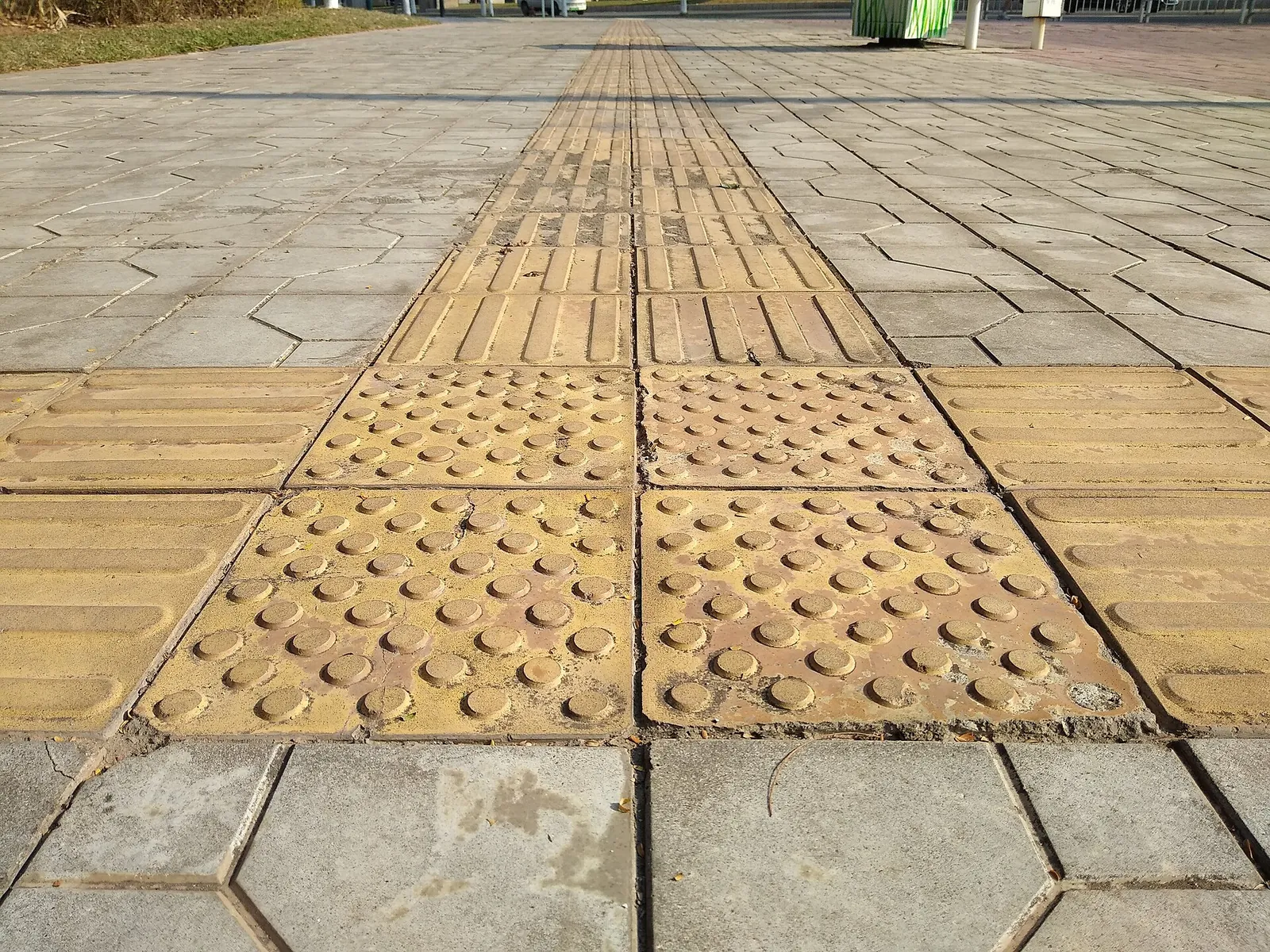 Yellow tactile paving for blind and partially sighted pedestrians along a pavement in Shenzhen.