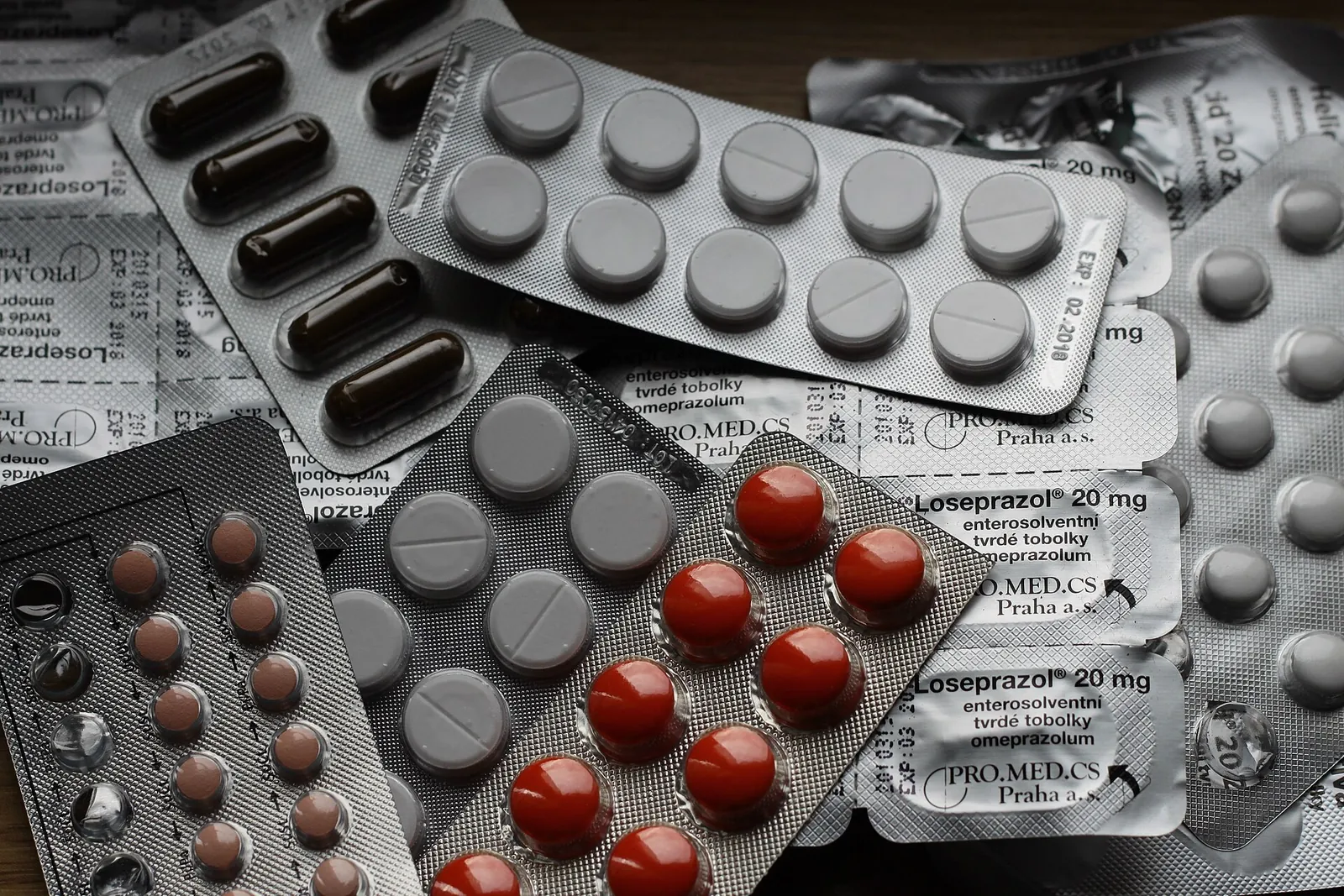 Overlapping blister packs of assorted tablets and capsules.